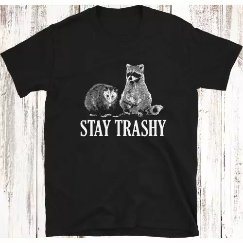 Voeg een vleugje speelsheid toe aan je stijl met ons "Stay Trashy Opossum & Raccoon" Grappige Meme T-shirt, met een schattig duo en de ondeugende slogan "STAY TRASHY."
